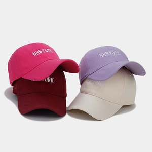 Four colorful baseball caps with NEW YORK embroidery in rose, burgundy, purple, and cream