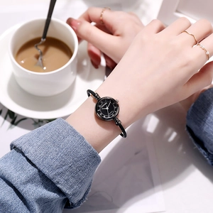 Elegant black bangle watch with Roman numerals on a classic round dial shown on a female wrist