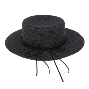 Detail view of the fine woven texture and black ribbon bow on a wide brim straw hat