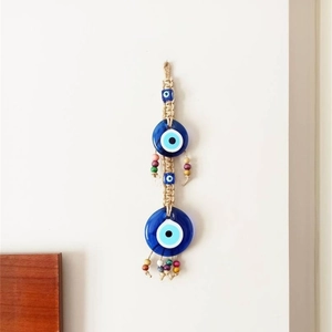 Detail of woven rope evil eye wall hanging with blue glass discs and colorful wooden beads