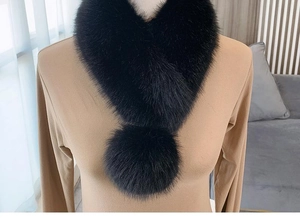 Detail of black faux fur neck warmer with decorative plush balls on a khaki top