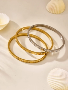 Macro detail of geometric stainless steel bangles with sparkling zircon inlay in gold and silver