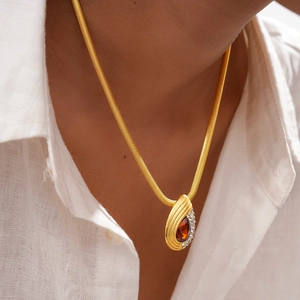 Close-up of gold snake chain necklace with waterdrop red gemstone and pavé diamonds