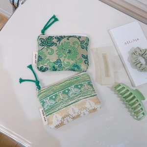 Detail of two floral jacquard mini pouches with green rope pullers and side label