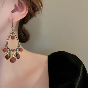 Detail view of retro Bohemian drop earrings with bronze metal and reddish-brown beads