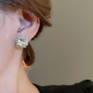 Close-up of square zircon stud earrings with silver setting on female model's ear