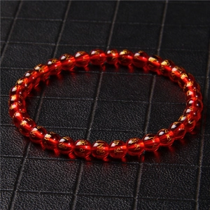 Macro detail of 6mm red agate beads with golden engraved mantras on stretch bracelet