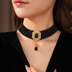 Macro detail of vintage choker with layered black beads and gold filigree pendant