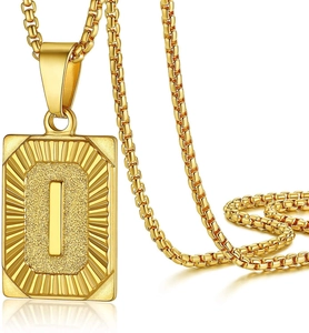Macro detail of gold initial I pendant with textured background and box chain necklace