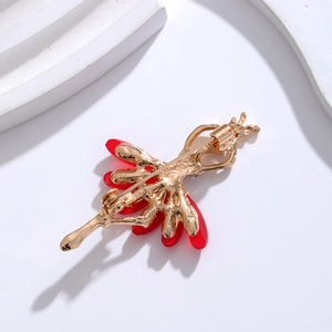 Back view of gold ballet dancer brooch with red resin inlay on minimalist white background