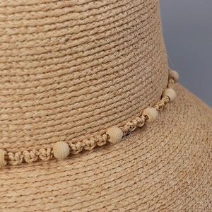 Macro shot of natural raffia straw hat texture with decorative wooden beads and cord