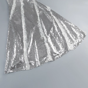Detailed close-up of silver sequins and layered white mesh ruffles on a party dress