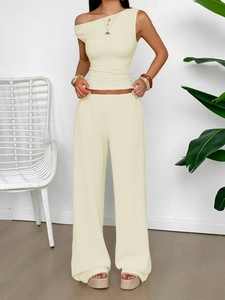 Detail of beige textured two-piece set featuring a one-shoulder top and wide-leg pants