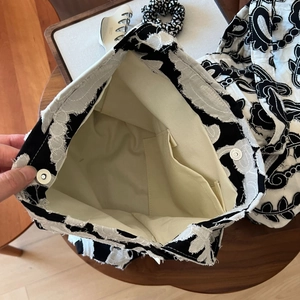 Detail of embroidered floral canvas bag interior with inner pocket and magnetic snap button