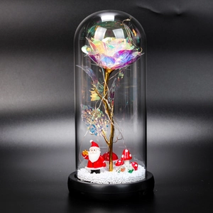 Close-up of lighted iridescent rose in glass dome with Santa and LED fairy lights