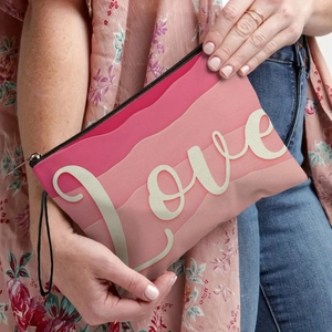 Pink gradient love printed clutch bag with black wristlet strap held by a model