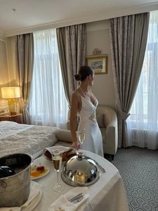 Elegant white satin slip dress with lace waist detailing in a bright luxury hotel setting