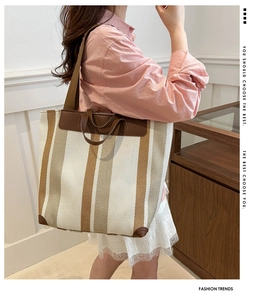 Detail of striped canvas tote showing leather trim and vertical beige-brown patterns