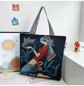 Close-up of ethnic woman embroidery and butterfly art on blue canvas tote bag