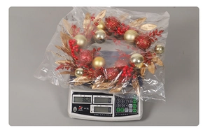 Christmas wreath with red berries and gold leaves on an electronic scale weighing 362g