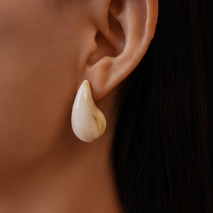 Detailed close-up of water drop acrylic earring with natural beige marble texture on a model