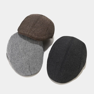 Detailed texture view of herringbone flat caps in dark brown, grey and black wool blend