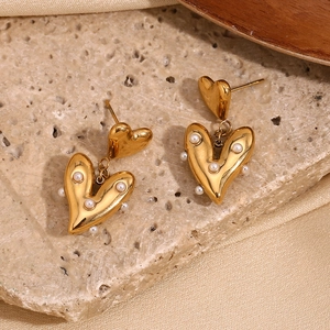 Macro shot of 18K gold plated irregular heart earrings with pearls on stone background
