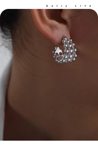 Macro shot of silver C-shape stud earrings with unique bubble texture design on model