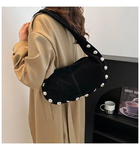 Detail of black suede underarm bag featuring silver rivet studs worn by a model