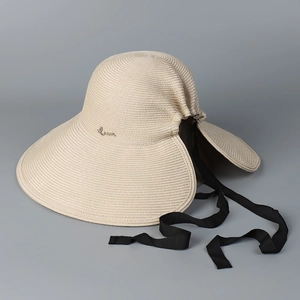Detail of beige straw hat with rear slit design and wide black ribbon for ponytails