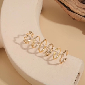 Detailed view of six gold-plated adjustable rings with heart, feather, and star patterns