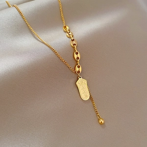 Detailed macro of gold-plated pig-nose chain with engraved lucky charm on silk fabric