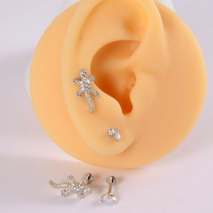 Detailed view of silver lizard and geometric stud earrings with rhinestones on an ear model