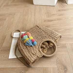 Detail of woven straw beach bag with colorful tassels and drawstring lining