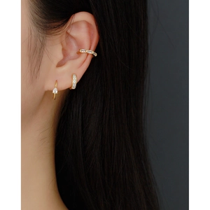Close-up of gold drop earrings and crystal ear cuff set worn on the model's ear