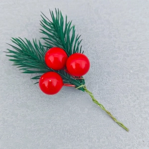 Close-up of artificial pine needles with red berries and green wire stem for DIY crafts