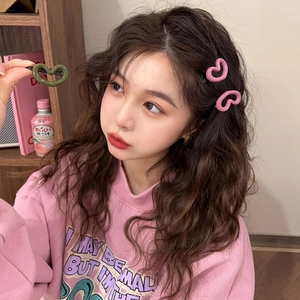 Détail d'une pince à cheveux en forme de cœur rose portée sur le côté pour femme