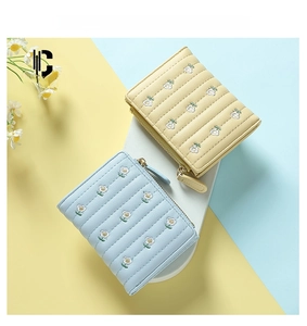 Close-up of quilted floral embroidery on blue and yellow leather mini wallets