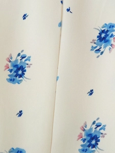 Macro detail of beige fabric with blue and pink floral print and woven texture