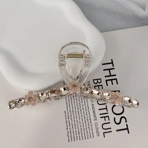 Macro detail of 13cm K9 crystal hair claw clip with peach floral accents on white background