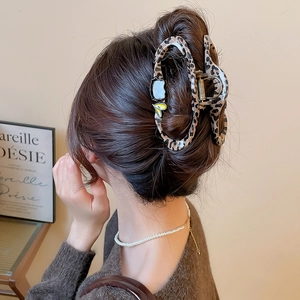 Detail of leopard print hair claw clip with heart accents on elegant side bun style