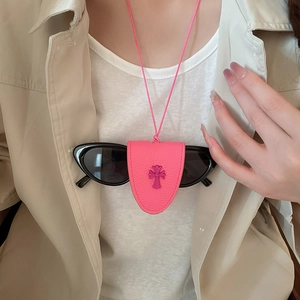 Close-up of pink leather glasses holder necklace with purple cross detail on beige clothing