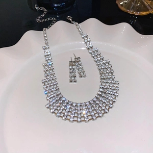 Detailed view of rhinestone fringe necklace and matching earrings on a white tray