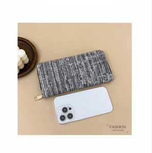 Close-up of black and white striped lady's long purse with gold zipper beside a phone