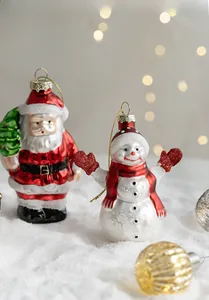 Close-up of Santa and Snowman glass ornaments with glitter details on white snow