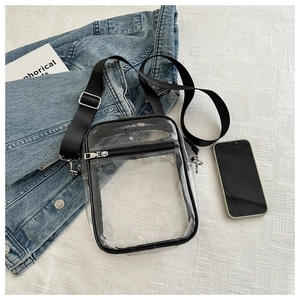 Transparent PVC crossbody bag with black trim shown from above on a white fabric background