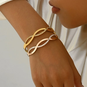 Detail of gold and rose gold twisted bangles with pavé rhinestones on wrist