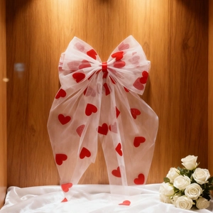 White organza bow hair clip with red heart patterns on a rustic wooden background