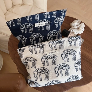 Detail view of navy and beige canvas pouches with sheep embroidery and woven label