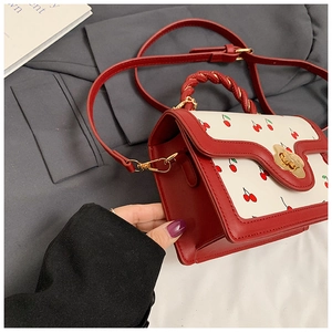 Dettaglio borsa con stampa ciliegia, chiusura a fiore dorato e patta ondulata elegante